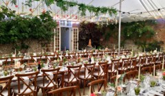 Bignor Park weddings courtyard reception tables and formal chairs set up with overhead canvas