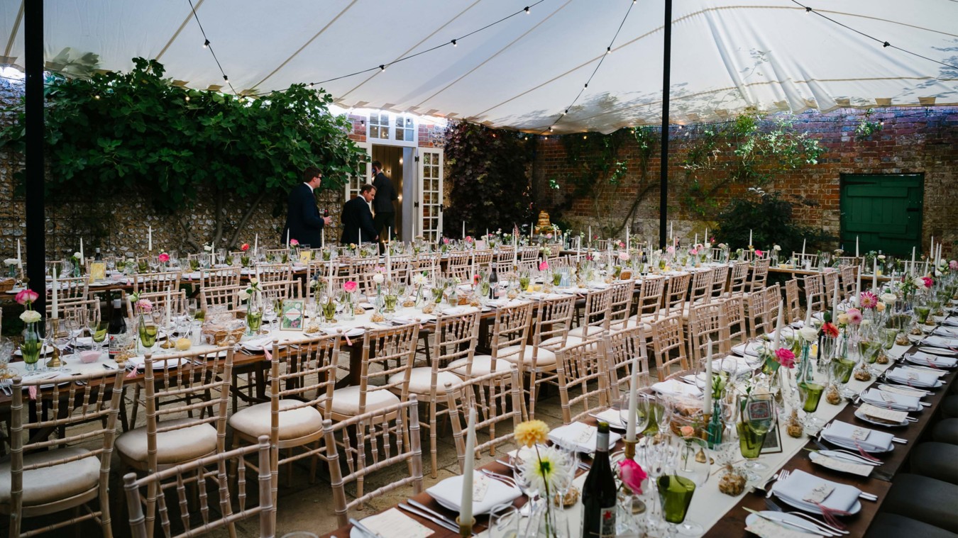 Bignor Park weddings courtyard reception tables and white chairs set up with overhead canvas